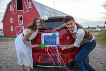 Portrait Happy, Playful Bride And Groom Pointing To ‚Äö√Ñ√≤Just Married‚Äö√Ñ√¥ Sign On Car Outside Barn
