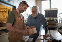 Two Men Examining Handmade Wooden Box In Workshop