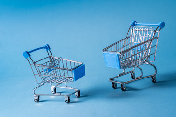 Canvas Print - Empty miniature shopping carts on blue background.