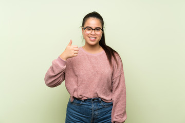 Wall Mural - Young teenager Asian girl over isolated green background with glasses