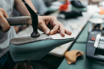 Close up shot of old shoemaker in his store. Traditional way of shoe making process.