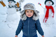 © Volodymyr - Happy smiling little boy child make snowman on sunny winter day. Happy kid winter portrait. Snowman and funny little boy kid in the snow.