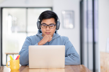 Young collage student using computer and mobile device studying online.