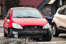 A Small Red Hatchback Car With Missing Frontal Par After A Traffic Accident With Radiator Visible.