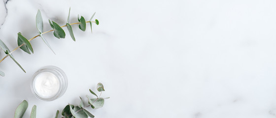 Wall Mural - natural organic cream jar with eucalyptus leaves on marble background. flat lay, top view, copy spac