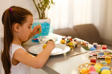 Wall Mural - Little girl painting Easter eggs in the kitchen