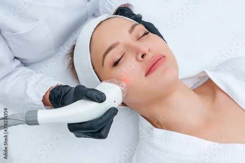 Fotografía Young woman receiving laser treatment in cosmetology clinic
