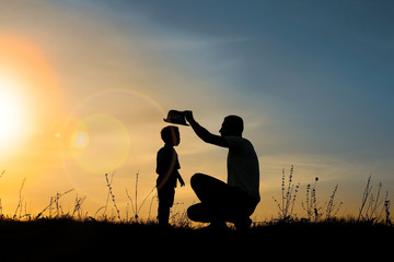 silhouette of father and son play on sunset