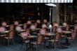 Tische und Stühle ohne Gäste vor einem Café mit gestreifter Markise im Winter bei Sonnenschein an der Konstabler Wache in der City von Frankfurt am Main in Hessen
