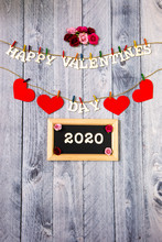 Happy Valentines Day With Red Hearts And Flowers On A Wood Background With 2020 On A Chalkboard
