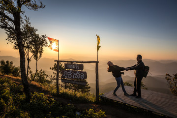 Romantic couple in love on mountain view misty morning at Phu chi phur viewpoint, Mae Hong Son Northern, Thailand. Thai language is name of viewpoint Phu chi phur. Relaxation and travel concept.