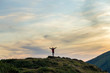 © bilanol - Dark silhouette of a hiker climbing a mountain at sunset raising his hands standing on summit like a winner.