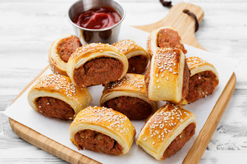 Wall Mural - Delicious homemade sausage rolls served with tomato sauce on a white wooden background.