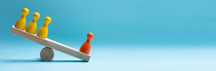 red and yellow pawns figures balancing on wooden seesaw
