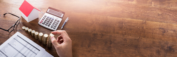 Person Stacking Coins On Wooden Desk