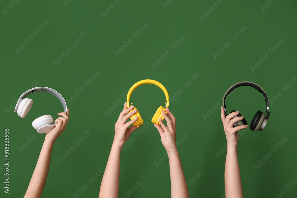 Hands with modern headphones on color background