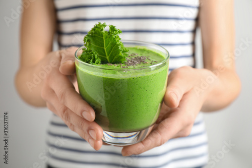 Fotografía Woman holding tasty kale smoothie with chia seeds on light background, closeup