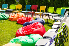 Bean Bags And Chairs In A Park On A Green Lawn. Red, Yellow, Blue Bean Bag On Grass