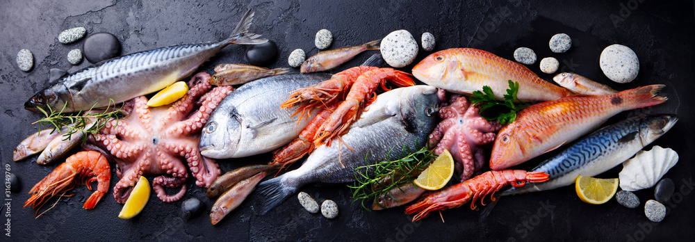 Fresh fish and seafood assortment on black slate background. Top view. - obrazy, fototapety, plakaty 