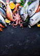 Fresh fish and seafood assortment on black slate background. Top view. Copy space.