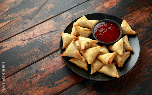 Cuadros en Lienzo Fresh Indian Samosa with dipping sweet chili sauce on wooden table