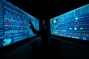 Wall Mural - The business lady standing between blue screens in the dark laboratory