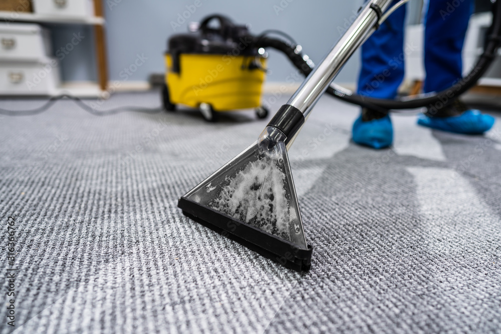 Person Cleaning Carpet With Vacuum Cleaner