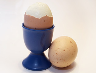 boiled, peeled egg in cup on white background