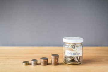 Coin in a glass jar on wooden desk, Saving money for education concept