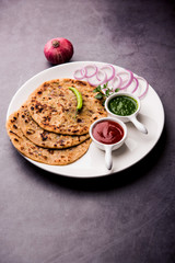 Canvas Print - Onion Parotha / Pyaj parantha / kanda paratha served with tomato ketchup and green chutney. selective focus