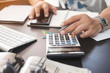 © kasarp - Businessman holding pen and using calculator at home office .Finance managers task