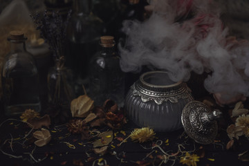 Wall Mural - vintage jars, bottles, containers, flowers in smoke and dry leaves on a wooden table with warm light