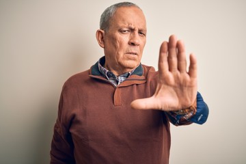 Poster - Senior handsome man  wearing elegant sweater standing over isolated white background doing stop sing with palm of the hand. Warning expression with negative and serious gesture on the face.