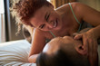 Adult smiling couple getting intimate while lying in bed