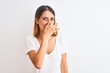 © Krakenimages.com - Beautiful redhead woman wearing casual white t-shirt over isolated background smelling something stinky and disgusting, intolerable smell, holding breath with fingers on nose. Bad smells concept.