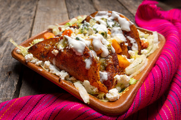 Mexican red enchiladas with potato and pork chorizo also called Potosinas on wooden background