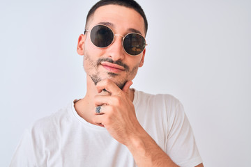 Sticker - Young handsome man wearing sunglasses and casual t-shirt over isolated background serious face thinking about question, very confused idea