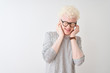 © Krakenimages.com - Young albino blond man wearing striped t-shirt and glasses over isolated white background covering ears with fingers with annoyed expression for the noise of loud music. Deaf concept.