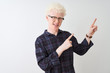 © Krakenimages.com - Young albino blond man wearing casual shirt and glasses over isolated white background smiling and looking at the camera pointing with two hands and fingers to the side.