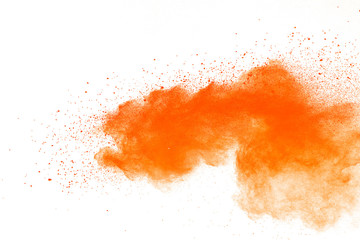 Abstract orange powder explosion. Closeup of orange dust particle splash isolated on white background.