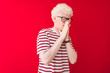 © Krakenimages.com - Young albino blond man wearing striped t-shirt and glasses over isolated red background smelling something stinky and disgusting, intolerable smell, holding breath with fingers on nose. Bad smell