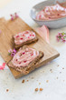 Slice of whole bread with red beet hummus spread a wooden cutting board
