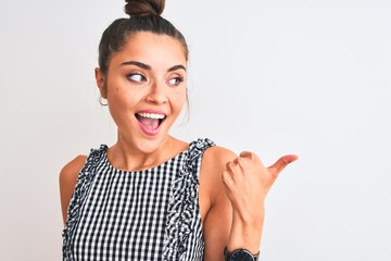 Poster - Young beautiful woman wearing casual dresss standing over isolated white background pointing and showing with thumb up to the side with happy face smiling