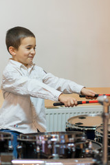 Boy drumming. boy in a white shirt plays the drums. vertical photo