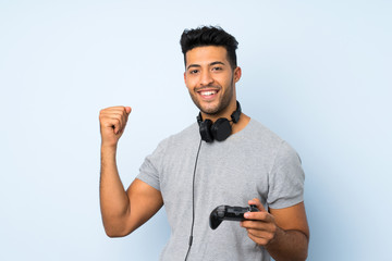 Wall Mural - Young handsome man over isolated background playing at videogames