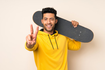 Wall Mural - Young handsome man over isolated background with skate and making victory gesture