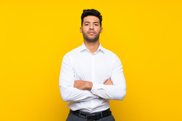 Wall Mural - Young handsome man over isolated yellow background keeping arms crossed