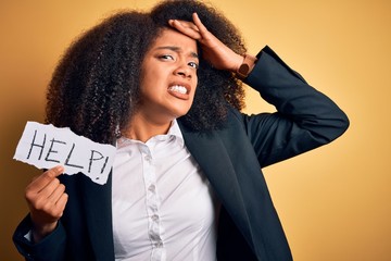 Young african american business woman with afro hair holding help paper for work stress stressed with hand on head, shocked with shame and surprise face, angry and frustrated. Fear and upset