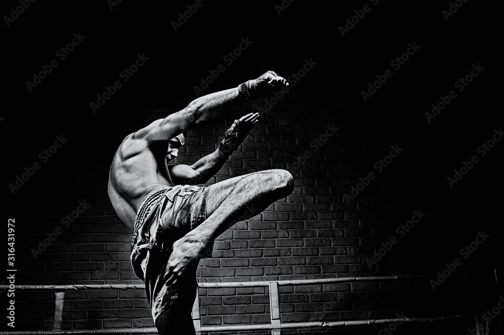 фотографія Thai boxer in the ring hits with a knee