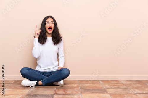 Fotomural Young woman sitting on the floor intending to realizes the solution while liftin